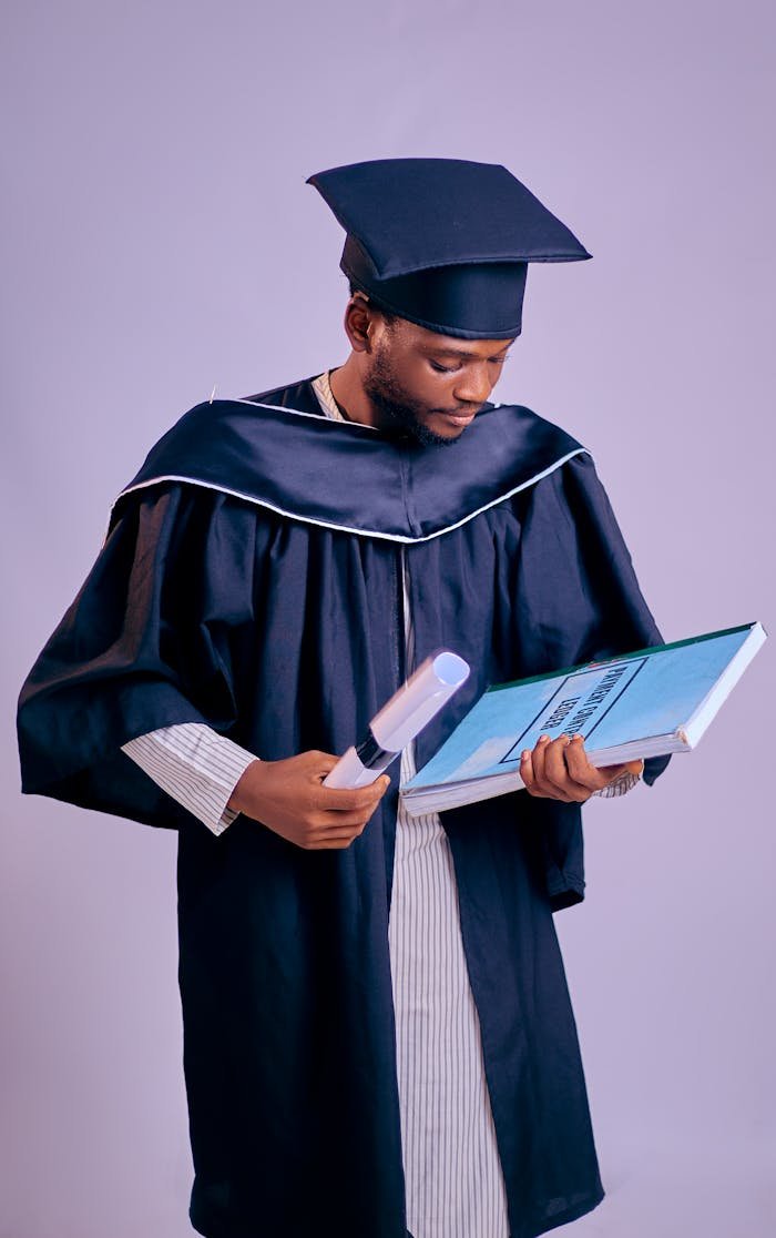 Home A young graduate in cap and gown holding a diploma and certificate.