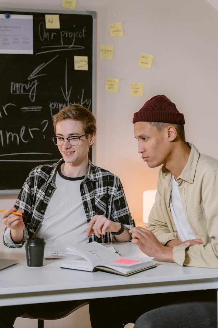 Two young men working together in an office setting, discussing ideas.