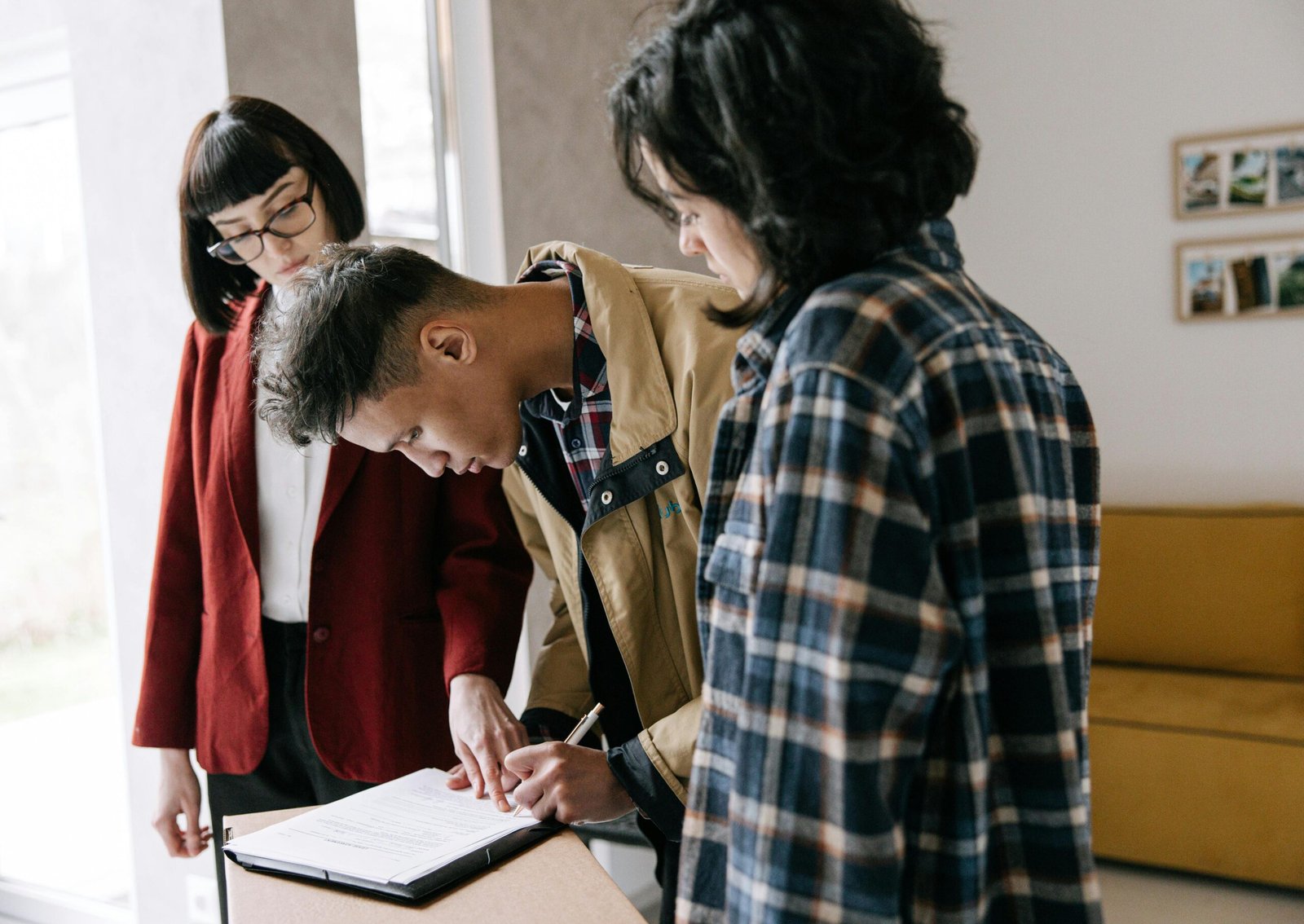 Young couple signing a real estate agreement with an agent indoors.